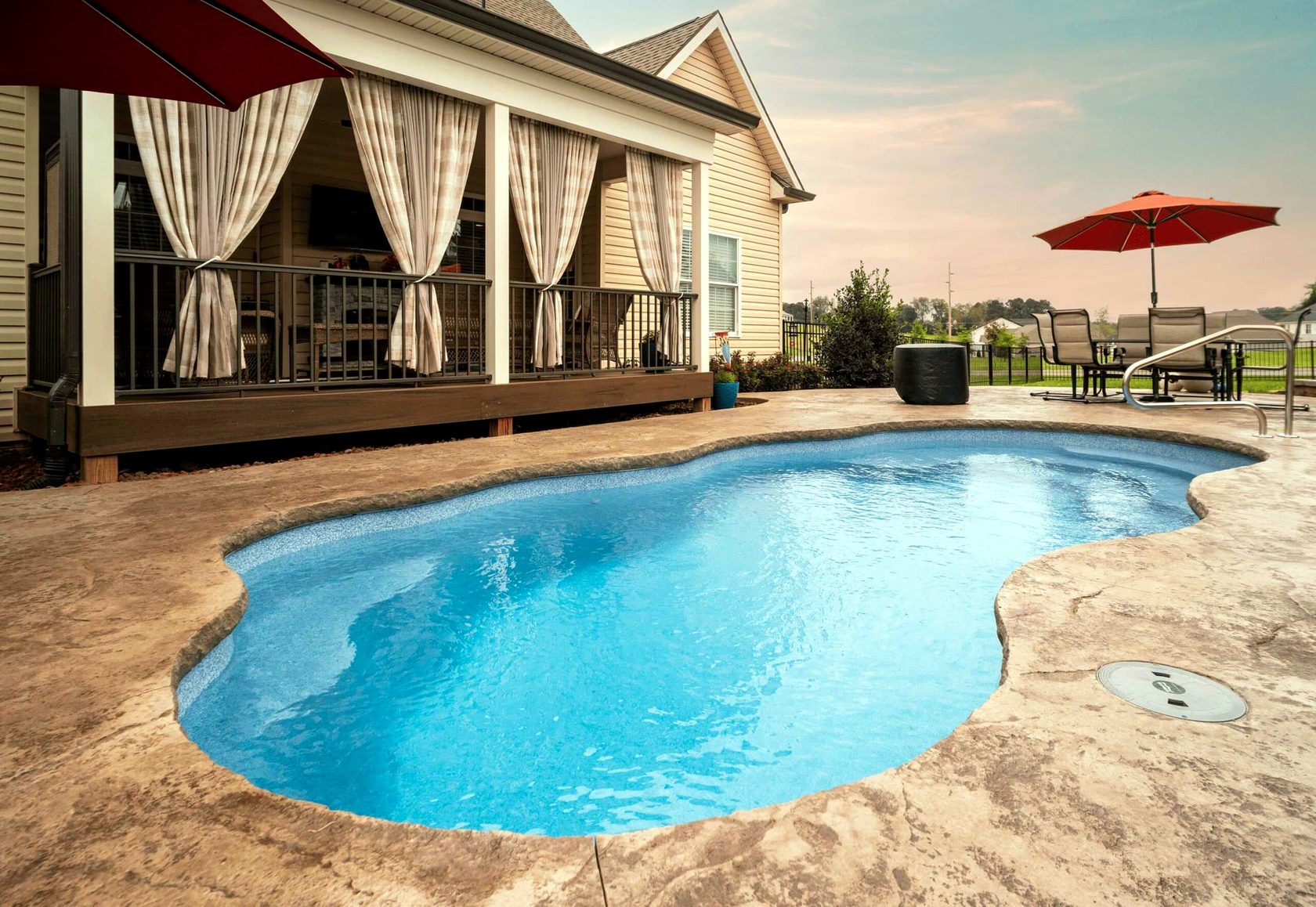 Freeform pool with stone coping at sunset